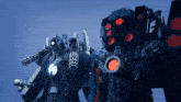 two robots are standing next to each other and one has a red light on the back of it