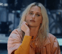 a woman with blonde hair is wearing a yellow shirt and a pink jacket .