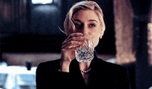 a woman in a suit is drinking from a glass .