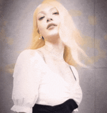 a woman with blonde hair is wearing a white top and black dress