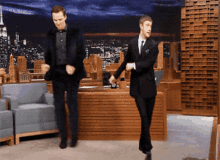 two men in suits and ties are dancing in a room