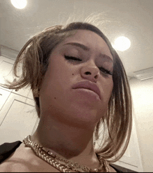 a close up of a woman 's face with a necklace that says ' chanel ' on it