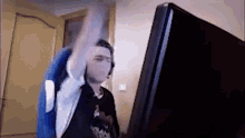 a man in a blue chair is sitting in front of a computer monitor and raising his arm in the air .
