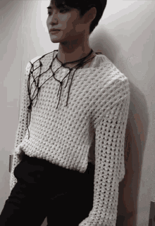 a man wearing a white sweater and black pants