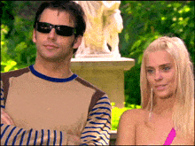 a man and a woman are standing next to each other in front of a statue