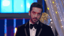 a man in a tuxedo with a bow tie is looking at the camera