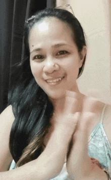 a woman is smiling and clapping her hands in front of a window