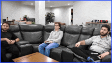 three men sit on a couch in a living room