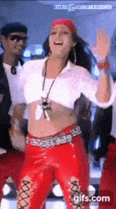 a woman in a white crop top and red pants is dancing