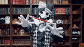 a man in a harlequin costume is holding a red wand in front of a sign that says circus