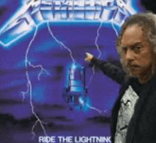 a man is pointing at a lightning bolt on the cover of metallica ride the lightning .