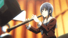 a girl in a red jacket is playing a clarinet