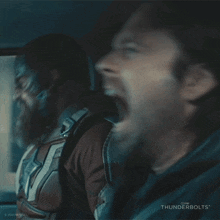 a man with a beard is screaming in a car with another man .