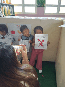a boy and a girl holding up a drawing of a letter x