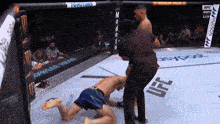 a referee is standing next to a fighter in a ufc cage .