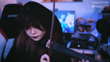 a woman playing a violin in front of a computer screen with luna lorraine written on the bottom