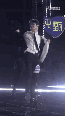 a man in a white shirt is dancing on a stage in front of a sign that says ' chinese ' on it .