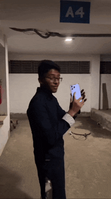 a man is holding a phone in front of a sign that says a4