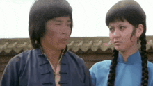 a man and a woman are standing next to each other and the woman has braids in her hair