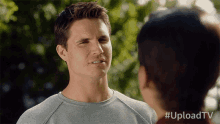 a man and a woman are looking at each other with #uploadtv written on the bottom
