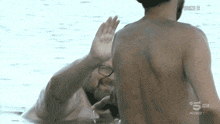a man in a bathing suit is waving at another man in the water which says 5 hd on the bottom