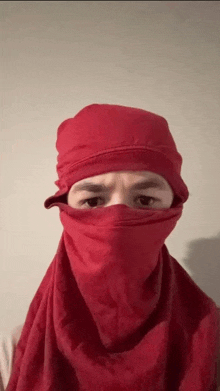 a man wearing a red scarf covering his face and head .