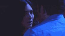 a man and woman are looking at each other in the dark