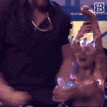 a blurred image of a man holding a bottle with the da zn logo in the corner