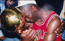 a man in a chicago bulls jersey kisses the trophy