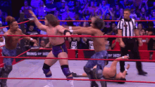 a group of wrestlers are in a ring with the word ring of honor on the wall behind them