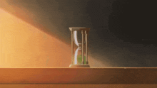 a hourglass with a green ball in it is on a table