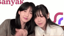 two girls are standing next to each other and the word banyak is behind them