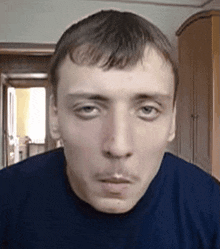 a close up of a man 's face with a blue shirt on