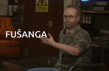 a man in a plaid shirt is sitting in front of a sign that says " danger "