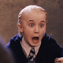 a young boy is making a surprised face while wearing a tie and shirt .