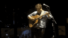 a man playing an acoustic guitar on a stage