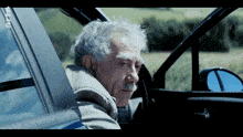 a man with gray hair and a mustache is in a car