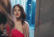 a woman in a red dress is standing in front of a mirror and looking at herself .
