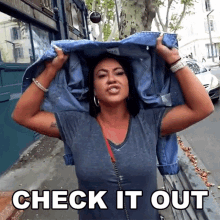 a woman is holding a denim jacket over her head and the words check it out are above her