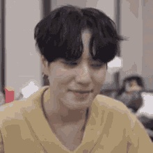 a close up of a person with black hair wearing a yellow shirt .