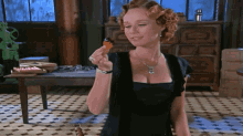 a woman in a black dress is holding a small item in her hand