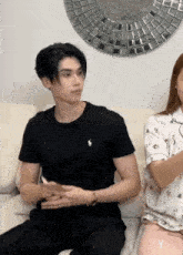 a man in a black polo shirt sits next to a woman in a white shirt
