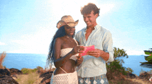 a man and a woman are looking at a pink envelope