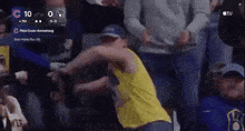 a man in a yellow tank top is dancing in the stands during a baseball game .