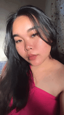 a woman with long black hair wearing a pink top