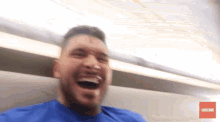 a man in a blue shirt is laughing on a plane