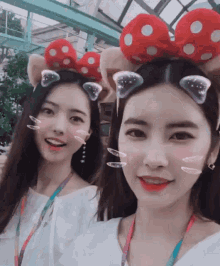 two girls wearing minnie mouse ears and bows