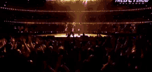a woman is standing on a stage in front of a crowd of people .