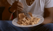 a person is eating scrambled eggs and toast with a fork ..