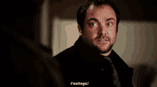 a man in a black shirt and tie is saying " feelings "